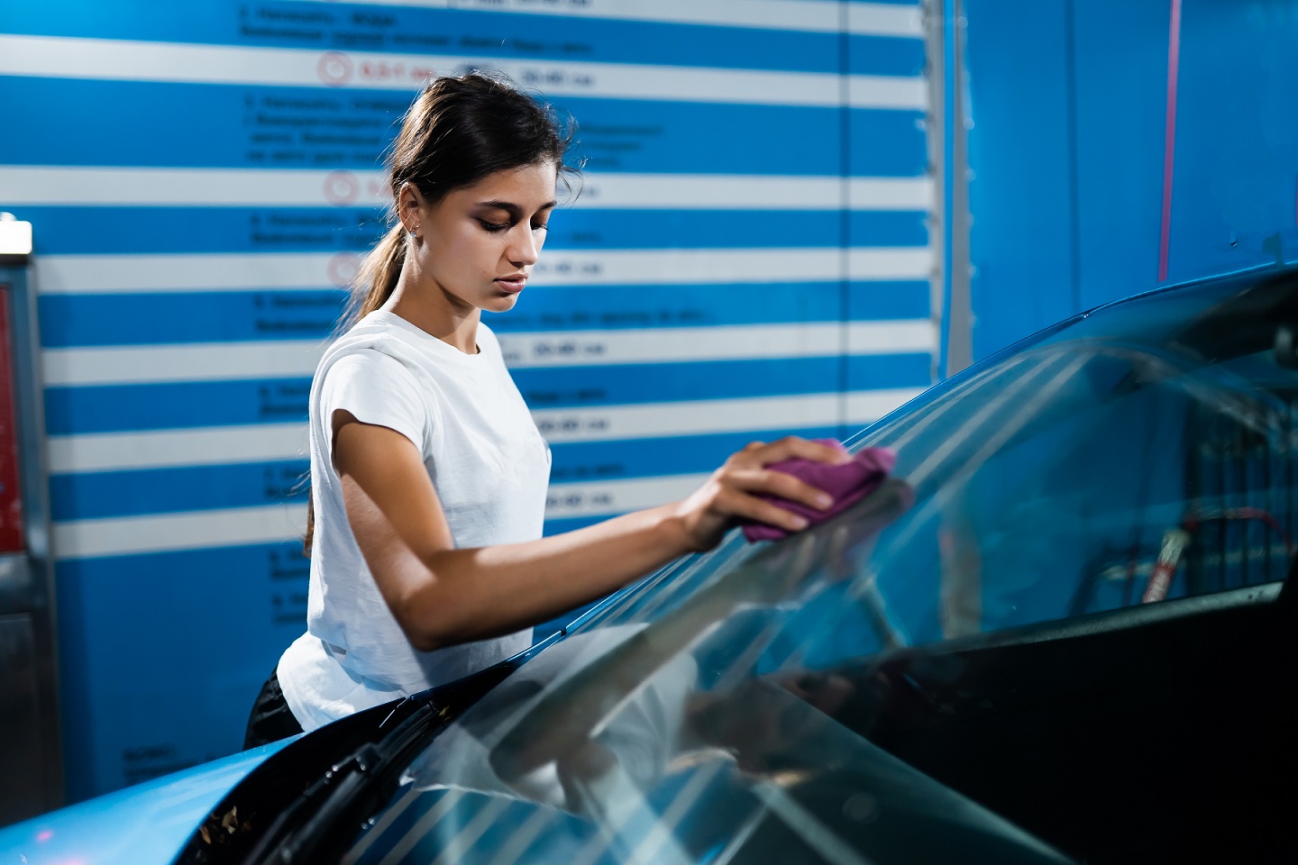 Shot of a young woman cleaning her car